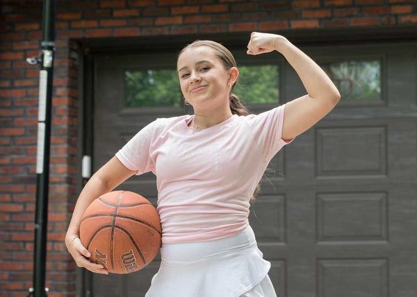 Girl with basketball flexing muscle