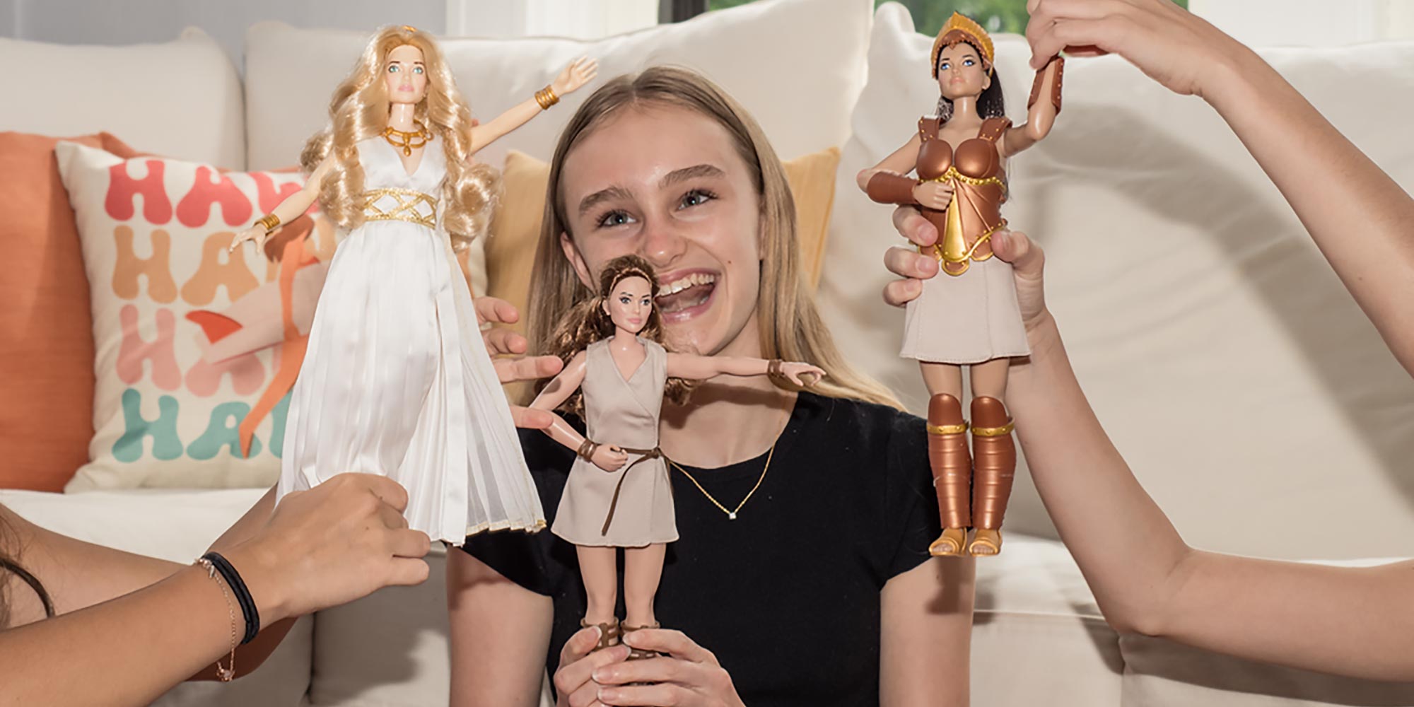 Girl holding an Artemis doll, with friends holding other Olympia Dolls